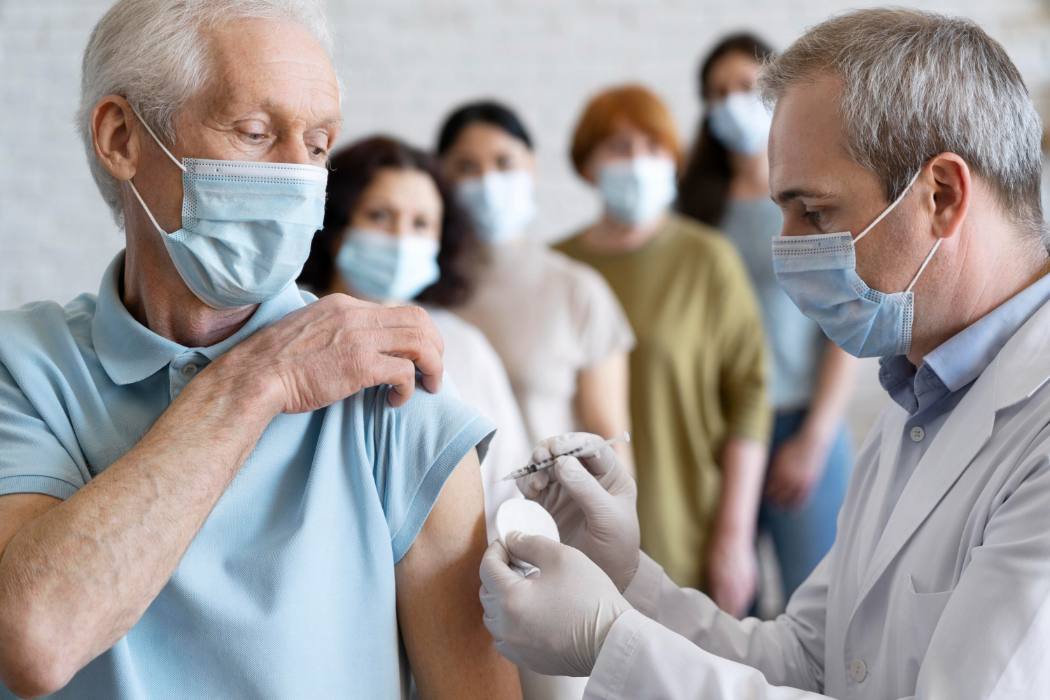 Vaccination d’un senior au Cabinet Infimier à Toulouse par une infirmière masquée avec file d’attente en arrière-plan,